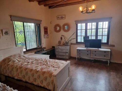 a bedroom with a bed and a tv and windows at Mountain House with Wonderful View in Las Compuertas