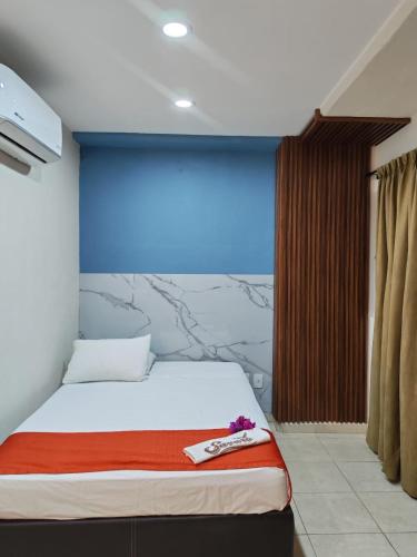 ein Schlafzimmer mit einem Bett und einer blauen Wand in der Unterkunft Hotel Tradicional Savaro SA de CV in Zihuatanejo