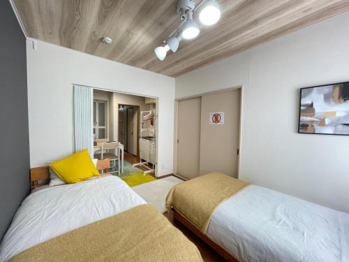 a bedroom with two beds and a tv on the wall at サイプレス平岸 in Sapporo
