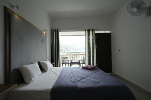 a bedroom with a large bed with a view of a balcony at Vagamon Hill Resort in Vagamon