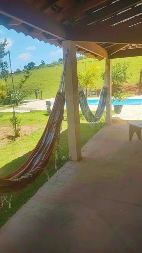 a couple of hammocks on a patio with a pool at Recanto do Batata in Atibaia