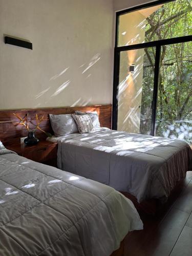 a bedroom with two beds and a large window at Casa Xunaan in Gómez Farías