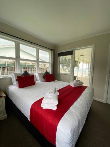 a bedroom with a large white bed with red pillows at Rehutai Beach House in Paihia