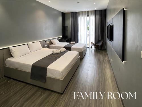 two beds in a room with a tv and a bedroom at Olive SamSon Hotel in Sầm Sơn
