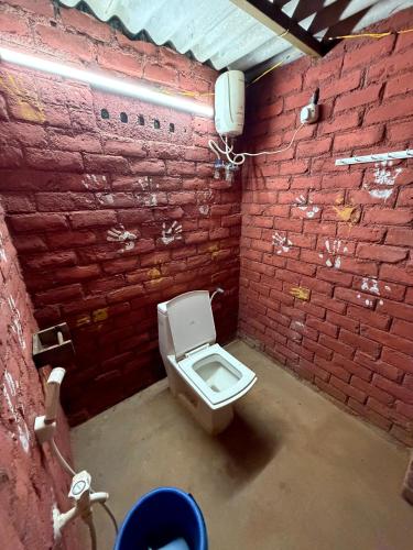 a bathroom with a toilet in a brick wall at v kudil in Auroville