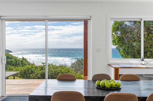 a dining room with a table and a view of the ocean at Waters Edge - beachside home near Rennies Beach in Ulladulla