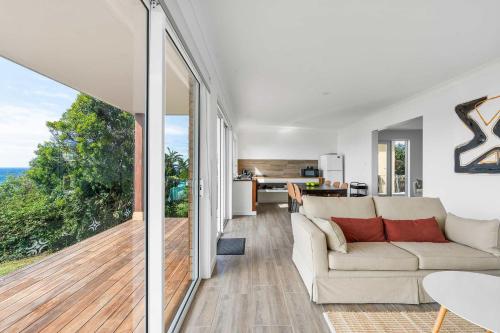 a living room with a couch and a large window at Waters Edge - beachside home near Rennies Beach in Ulladulla