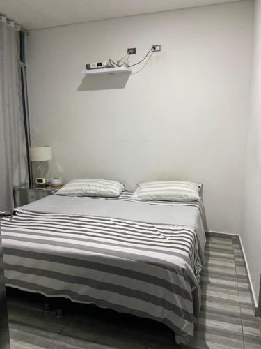 a bedroom with a bed with a black and white striped blanket at Casa o Habitación in Villeta
