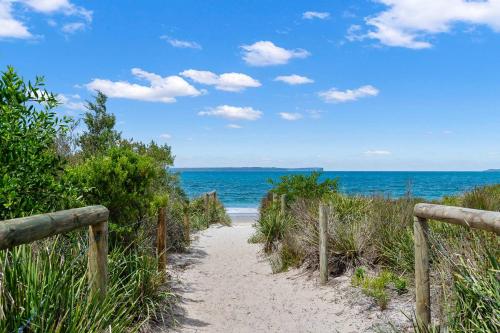 a path to the beach with the ocean in the background at Collingwood - 4BR modern beachfront holiday home in Vincentia