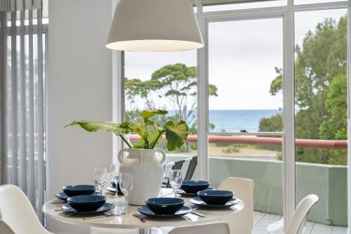 a dining room with a table with a vase on it at Fathoms 13 Mollymook Beach in Mollymook