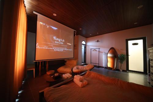 a large screen in a room with a bed and chairs at Àla Homestay Cần Thơ in Can Tho