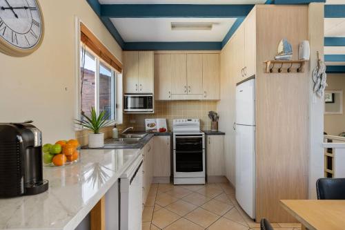 a kitchen with white appliances and a clock on the wall at Oceans 13 in Manyana