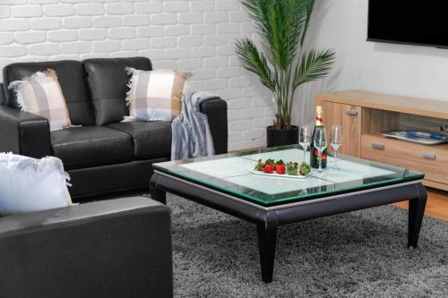 a living room with a black couch and a coffee table at Simmons Sanctuary Ulladulla in Ulladulla
