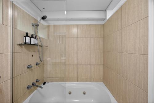 a bathroom with a shower and a bath tub at The Noosa Apartments in Noosa Heads