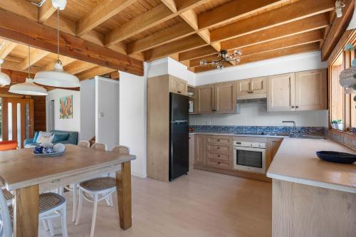 a kitchen with a table and a black refrigerator at The Beach Haven in Bawley Point