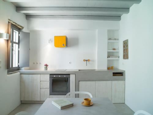 a kitchen with a table and a yellow box on the wall at Tutti Blu Tinos Living Space in Mési