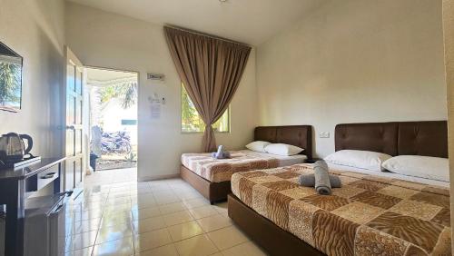a hotel room with two beds and a television at Casa Yusika in Pantai Cenang