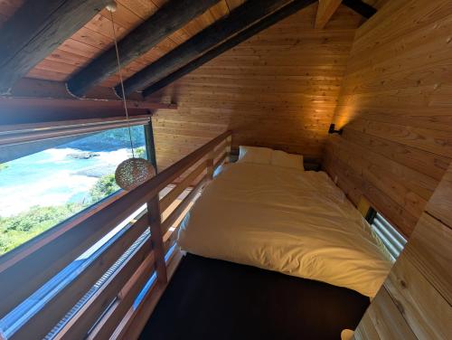 a bed in a wooden room with a window at The Villa Kotoshiro -ヴィラ コトシロ- in Matsue