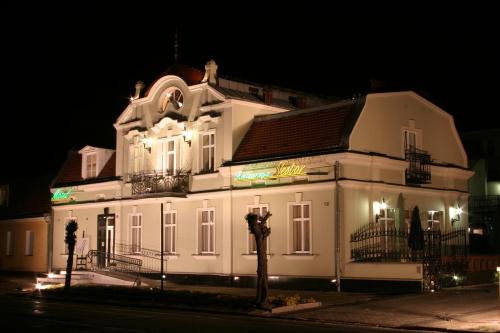 ein großes weißes Gebäude in der Nacht mit Lichtern in der Unterkunft Willa Nestor in Kórnik