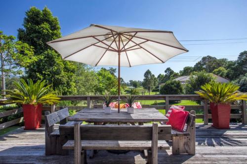 a wooden table with an umbrella and a bench at Stone Cottage - vineyard estate w. fireplace in Milton