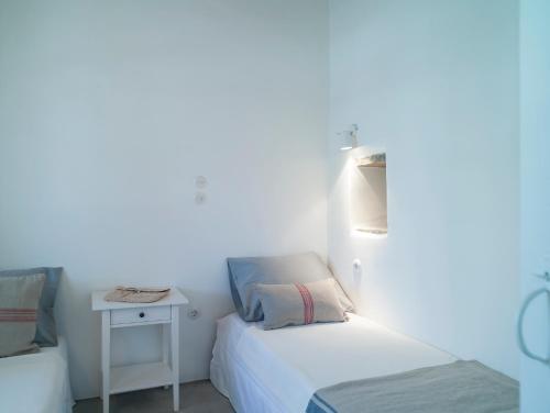 a white room with two beds and a table at Tutti Blu Tinos Living Space in Mési