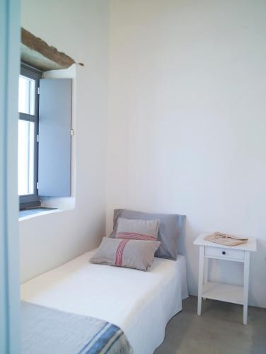 a white bedroom with a bed and a window at Tutti Blu Tinos Living Space in Mési