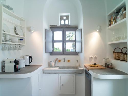 a white kitchen with a sink and a window at Tutti Blu Tinos Living Space in Mési
