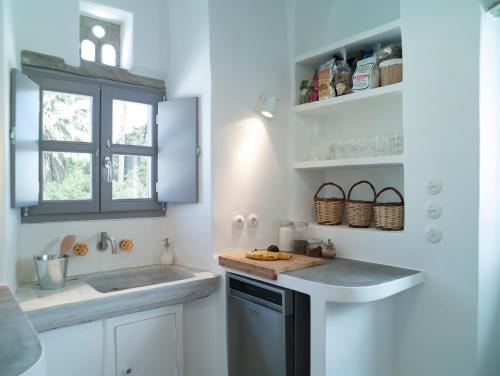 a white kitchen with a sink and a window at Tutti Blu Tinos Living Space in Mési