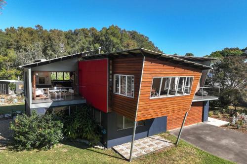 a small house with a red door on a yard at Murramarang Haven in Bawley Point