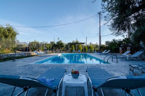 a swimming pool with chairs and a table with a bowl of fruit at Io in Stoupa