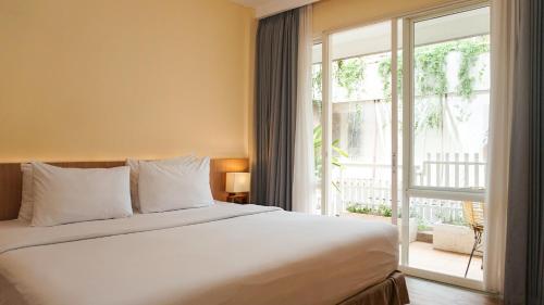 a bedroom with a bed and a large window at The Rivavi Legian in Legian