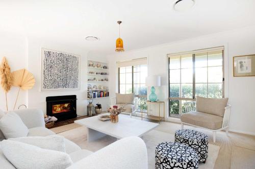 a living room with white furniture and a fireplace at Point Break in Bawley Point