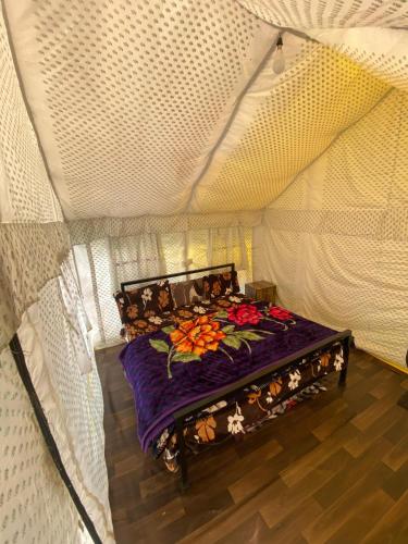 a bed in a tent with a purple blanket at Sari Highlands chopta Offbeat campsite in Ukhimath