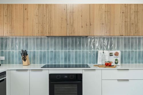 a kitchen with white counters and wooden cabinets at Thalassa Views Ulladulla in Ulladulla