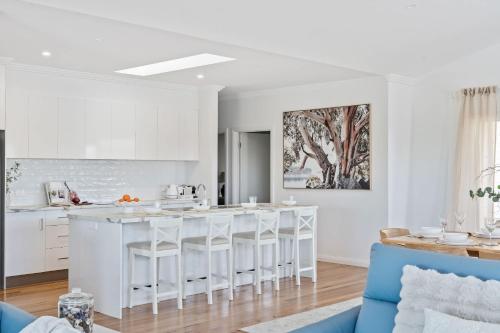 Eine Küche mit weißen Schränken und einer Kücheninsel mit Barhockern in der Unterkunft Crestmount in Milton