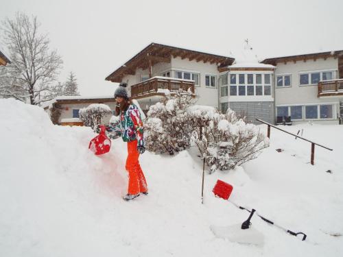 a woman standing in the snow in front of a house at Appartements Erhol dich gut in Leutasch