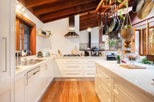 a kitchen with white cabinets and wooden ceilings at Banyula in Bawley in Bawley Point