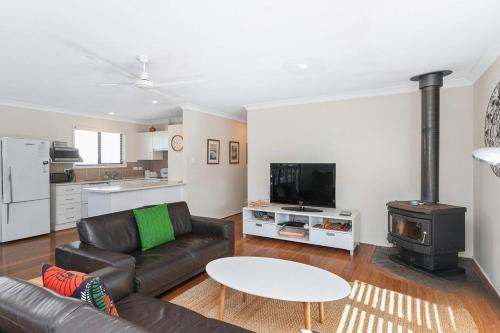 a living room with a couch and a stove at Bawley Beach Bungalow in Bawley Point