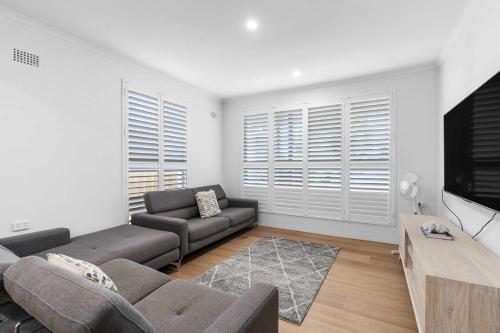 a living room with a couch and a tv at Sundance - Collingwood Beach holiday home in Vincentia