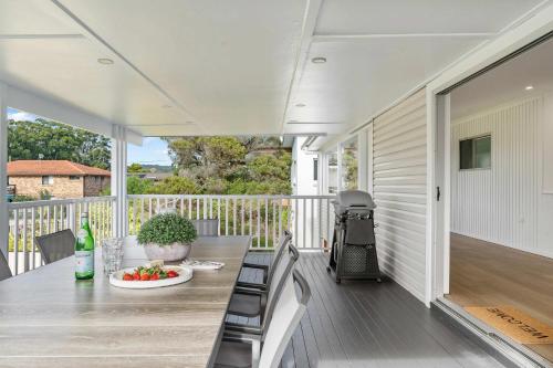 a porch with a table and chairs on a deck at Sundance - Collingwood Beach holiday home in Vincentia