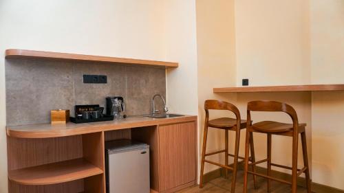 a kitchen with two bar stools and a sink at The Rivavi Legian in Legian