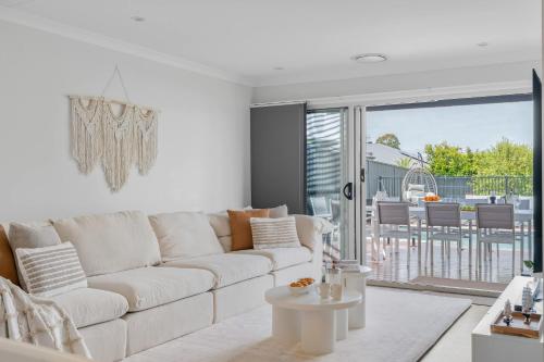 a white living room with a couch and a table at Sanctuary Splash Getaway in Sanctuary Point