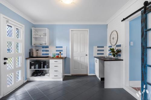 a kitchen with blue walls and a white cabinet at Kangaroo Sanctuary Studio in Sanctuary Point