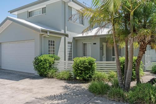 a white house with a garage and palm trees at Husky Salt in Huskisson