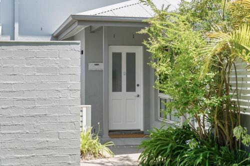 a house with a white door and a brick wall at Husky Salt in Huskisson