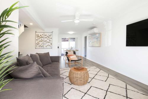 a living room with a couch and a tv at Aquamarine - modern & bright Huskisson townhouse in Huskisson