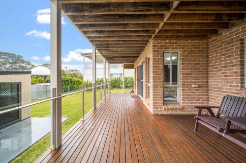 a wooden deck with a bench on a house at Footprints at Hyams Beach - 4BR home w. games room in Hyams Beach