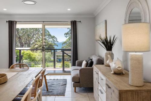 a living room with a table and a couch and a dining room at Days By The Bay - 3BR house with ocean views in Hyams Beach
