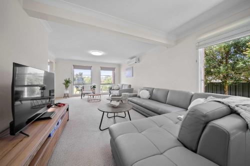 a living room with a couch and a flat screen tv at Amalena by the sea - Vincentia 5BR home with pool in Vincentia