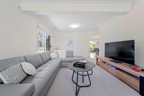 a living room with a couch and a flat screen tv at Amalena by the sea - Vincentia 5BR home with pool in Vincentia